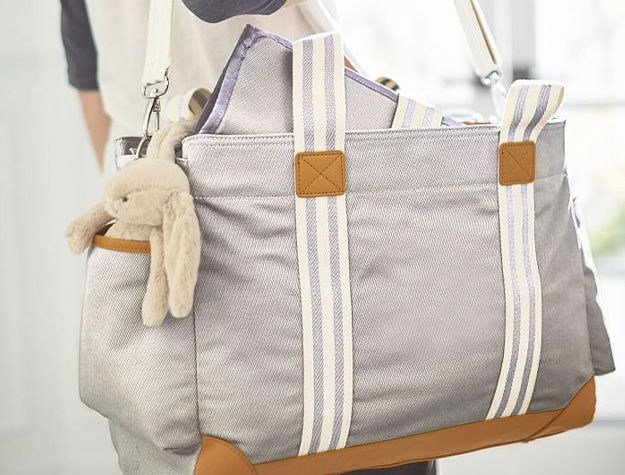 Parent holding gray diaper bag with supplies from hospital bag checklist.