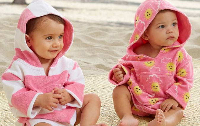 Infants wrapped in pink sun safe beach cover ups 