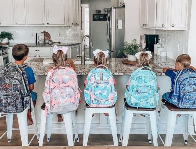 five kids with backpacks in kitchen