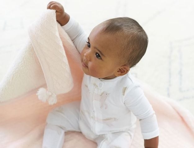 baby holding pink blanket