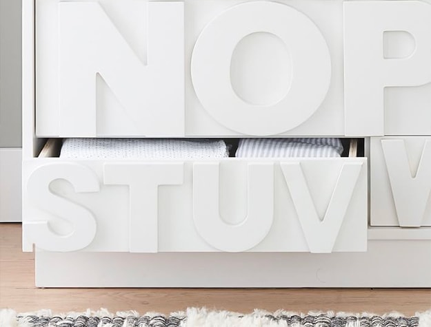 white dresser with cut out letters on drawers