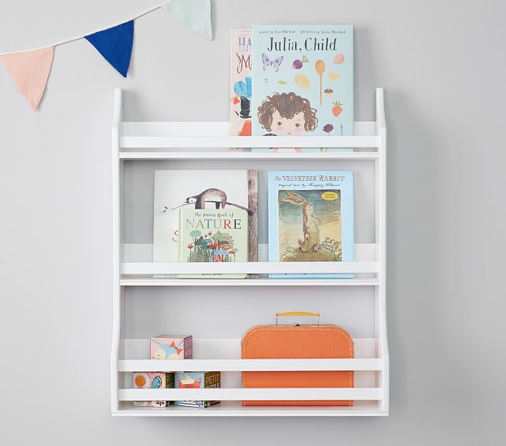 A white wooden bookshelf with some kids books is hung on the wall