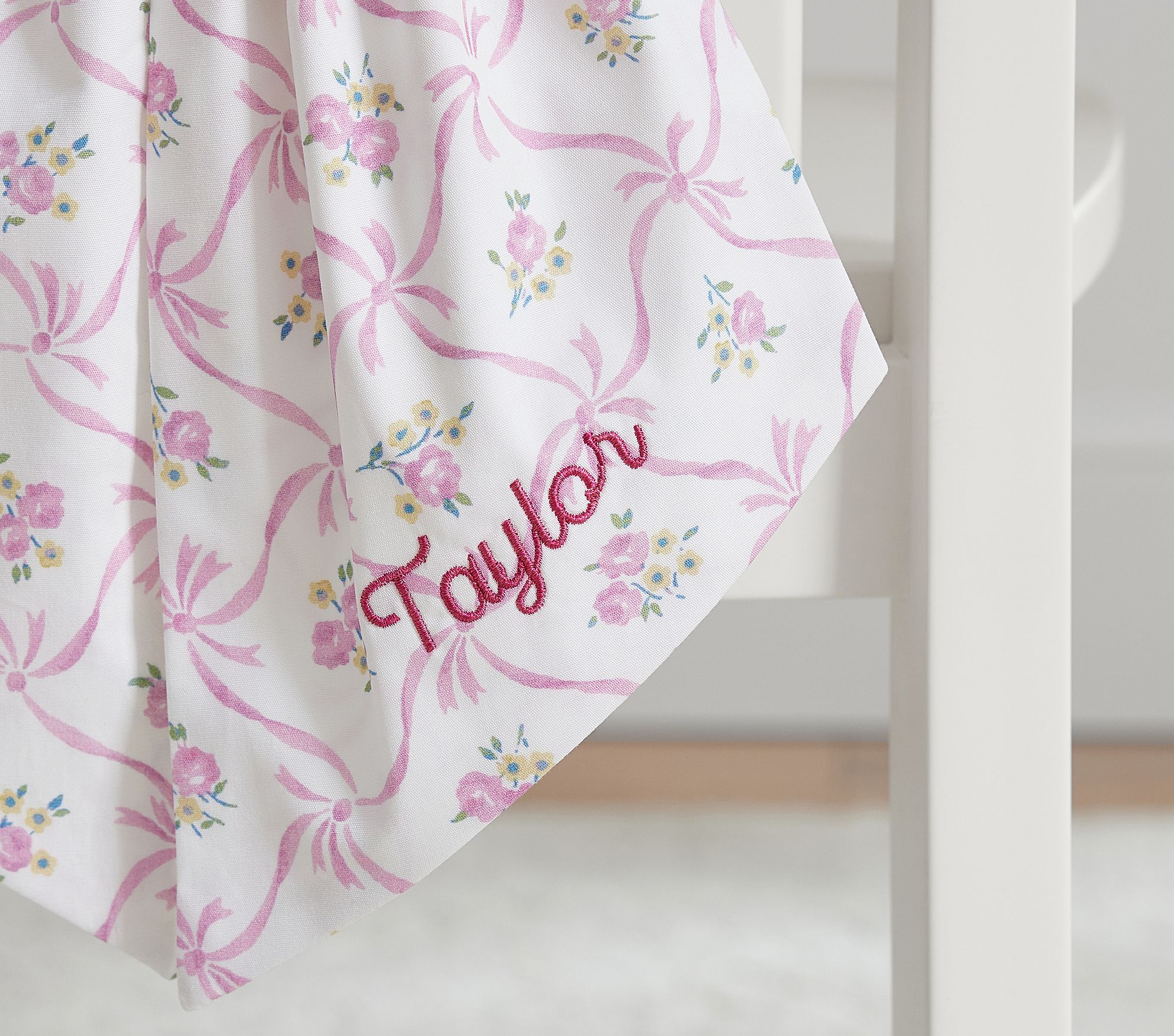 Embroidery close-up: 'Taylor' on pink floral bow.