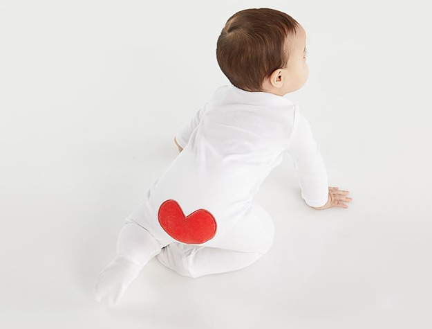 baby in white bodysuit with red heart