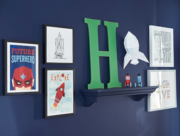 Gallery wall with framed photos, drawings and a large letter H.