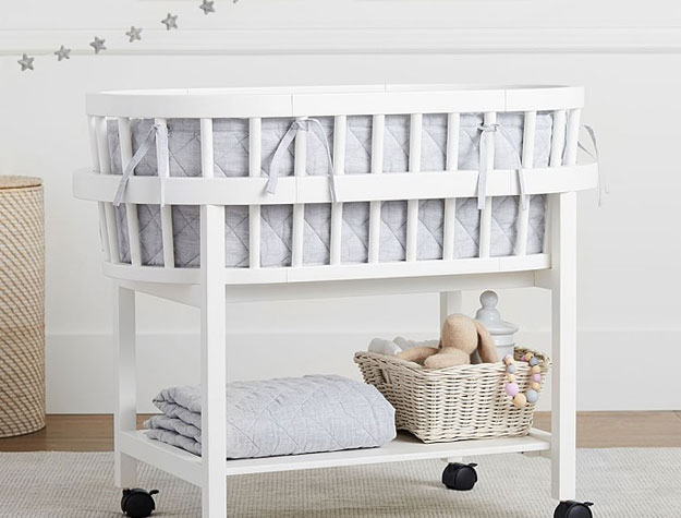 white bassinet with wheels and shelf