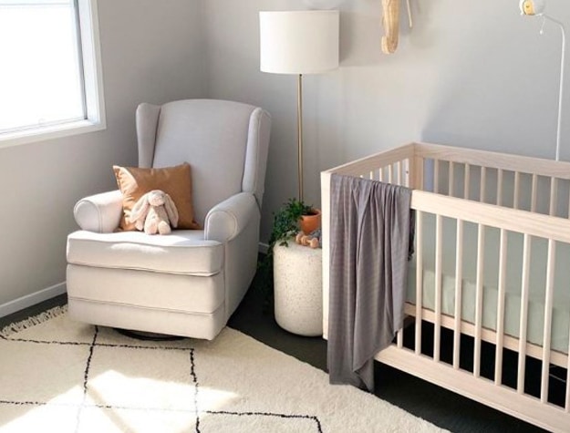 White glider in nursery with crib and stuffed animal 