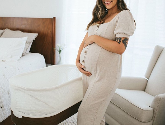 expecting mother standing next to bassinet