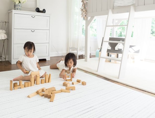 Children playing with blocks on reversible playroom rug