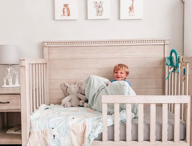 Toddler in his wooden convertible crib