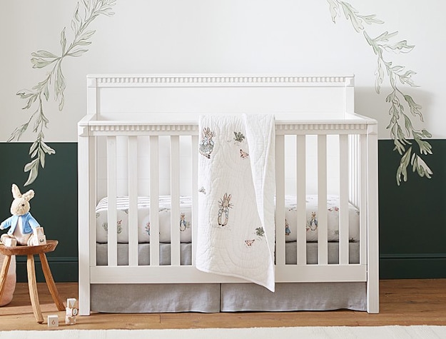 White crib with bunny blanket and green wall