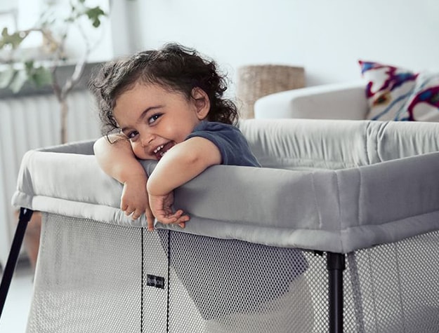 Baby hanging on to side of crib
