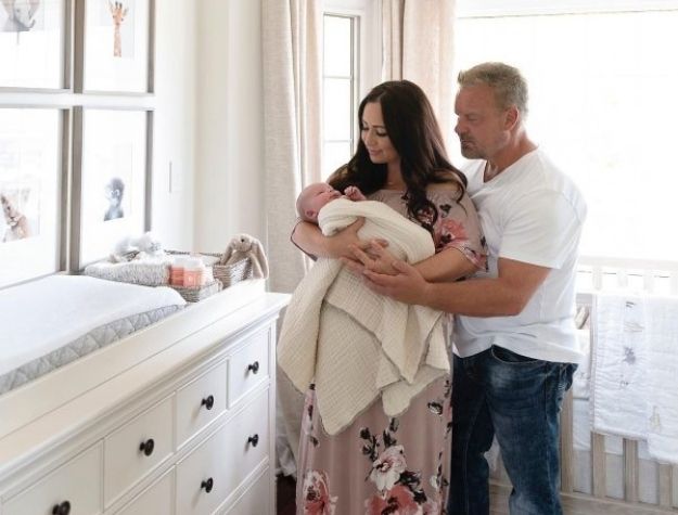 parents holding baby next to changing table