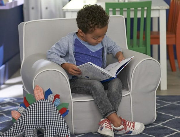Child reading in small chair with toys