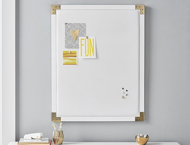 small white bulletin board with gold metal corner brackets
