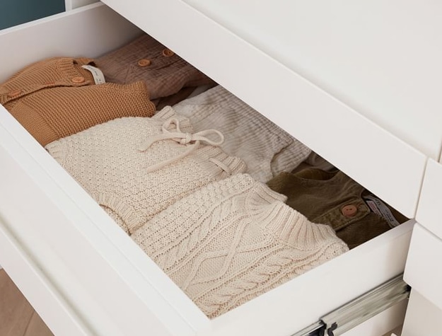 Open white drawer filled with knits