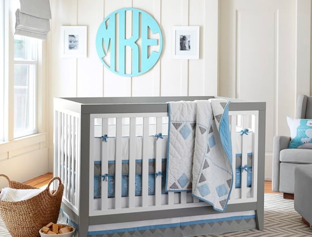 Teal monogram wall hanging behind crib