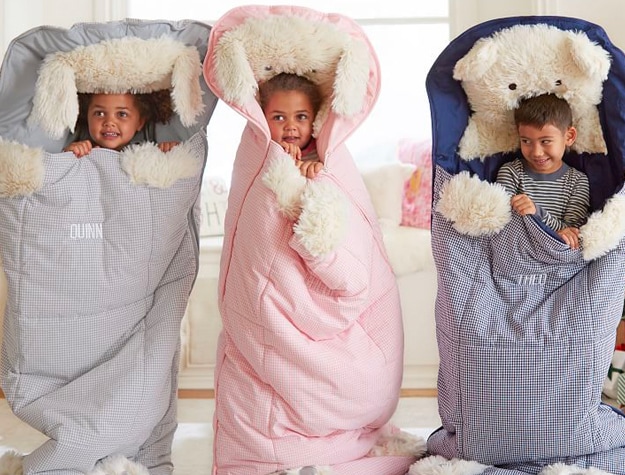 Three children in sleeping bags with their names embroidered