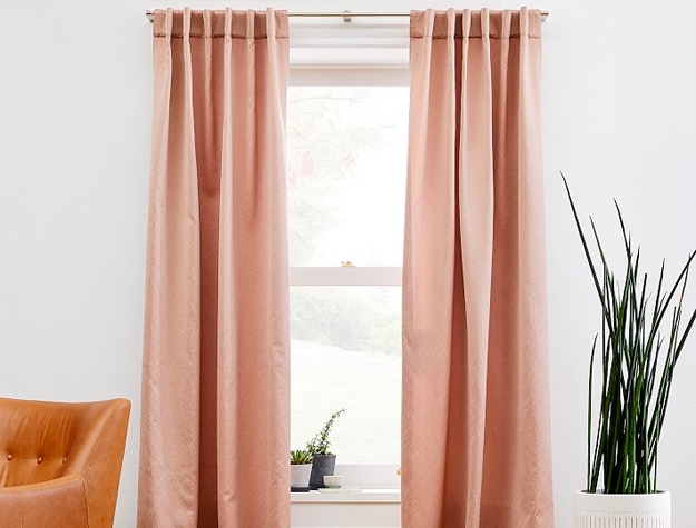 Blush pink curtains hanging over window