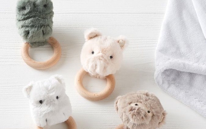 Four animal plush rattles placed next to a gray blanket