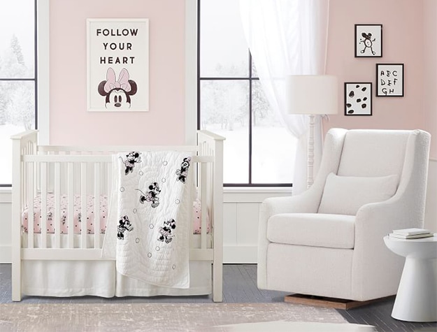 Pink nursery with crib, chair, Disney Minnie Mouse wall art and blanket.