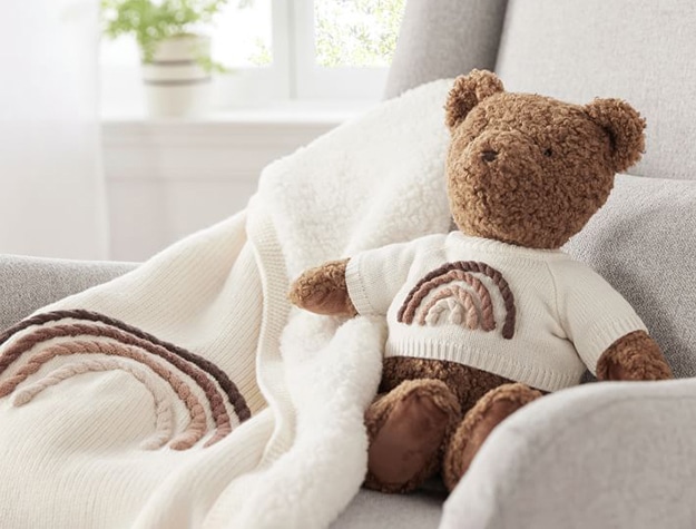 Brown teddy bear in a chair with a matching blanket.