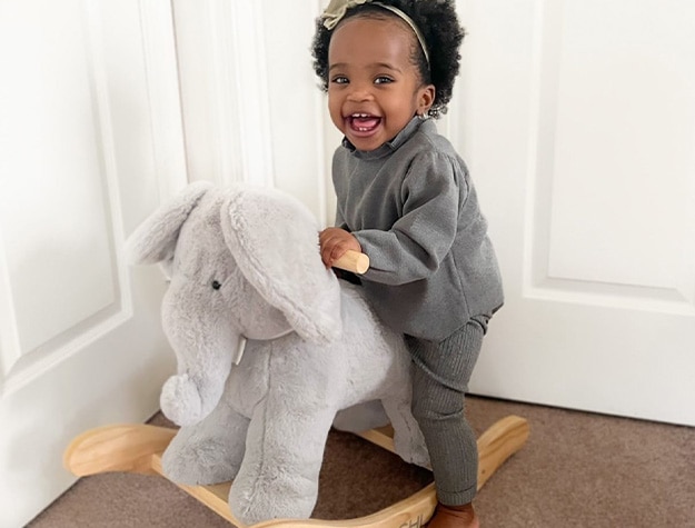 Baby playing with elephant critter nursery rocker.