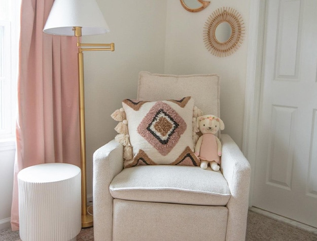 Paxton swivel glider chair with stuffed animal and pillow in a decorated nursery.