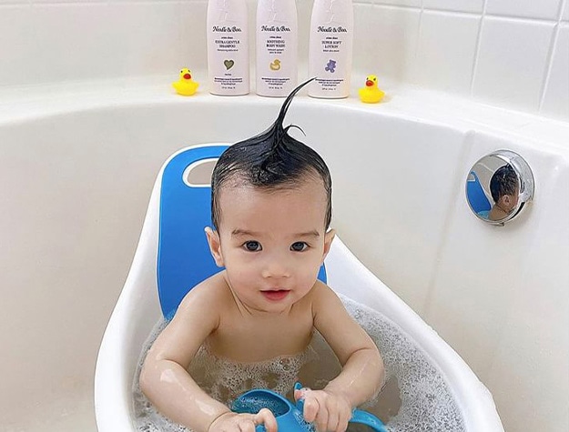 Baby in bathtub with hair slicked up. 