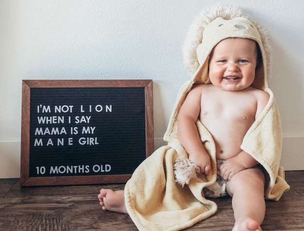 Baby lounging in lion bath towel next to felt letterboard reading I’m not lion when I say my mama is my mane girl 10 months old.