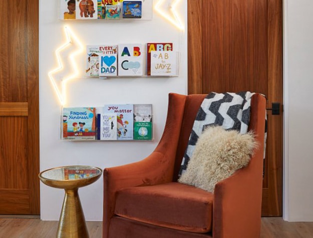 Nursery with wall mounted display shelf holding children’s books.