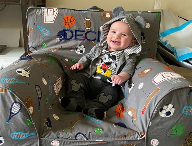 Baby sitting in a Tyler sports print Anytime Chair with “Declan” stitched on it. 