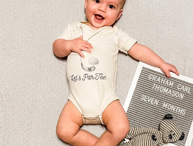 Baby sitting beside a felt letter board with stuffed animal. 