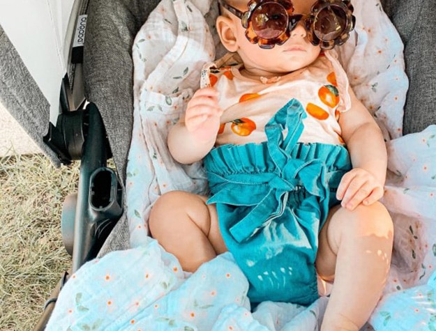 Baby wearing sunglasses in a carrier.