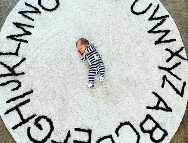 Baby lying on a Lorena Canals washable ABC rug.