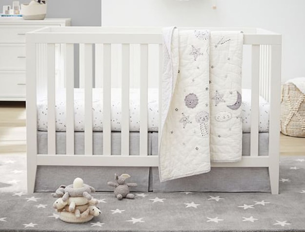 Gray rug with stars underneath crib in bedroom.