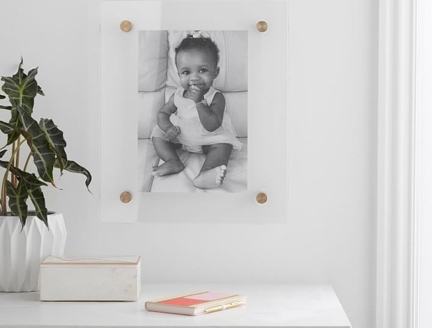 Acrylic gallery frame with black and white photo above table with plant.