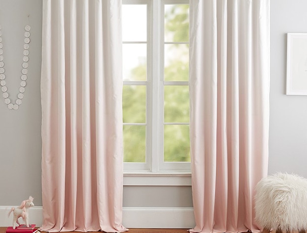 Ombre blackout curtain panel with furry ottoman and unicorn toy below. 