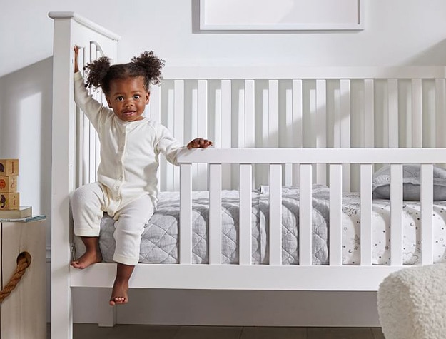 Child climbing out of convertible crib to toddler bed.