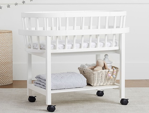 Simply white Bristol Bassinet and Mattress Pad Set on wheels with blanket and basket.