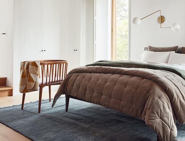 West Elm pbk Mid-Century Bassinet and Mattress Pad Set at the foot of bed in master bedroom.