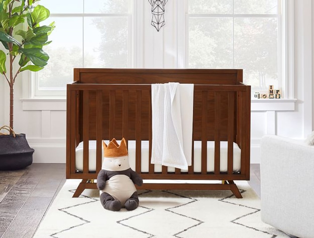 West Elm x pbk Baby Souk Nursery Rug in ivory and navy with mid century crib and panda stuffed animal.