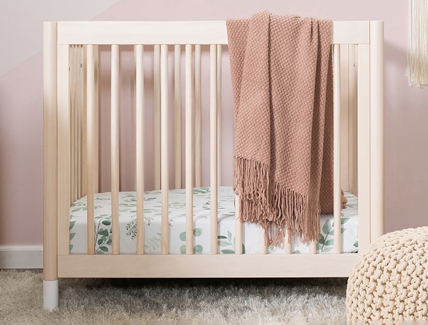 atural wood Babyletto Gelato Convertible 4 in 1 Mini Crib against pink nursery wall.