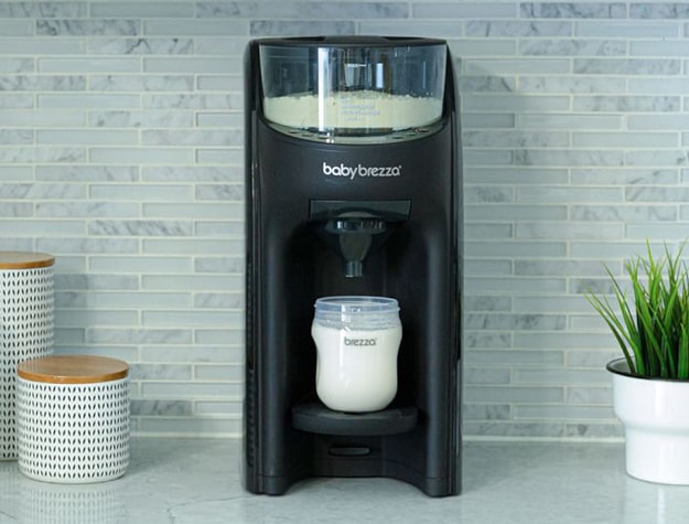 Baby Brezza dispensing extra formula into a cup.