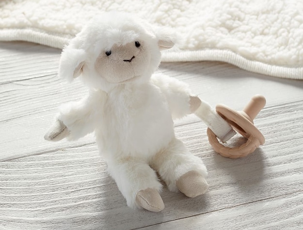 A pacifier attached to a Lamb Critter Plush pacifier holder.