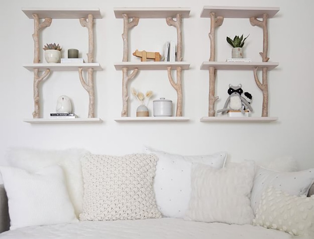 Three birch floating shelves over a daybed with animal figurines styled on them.