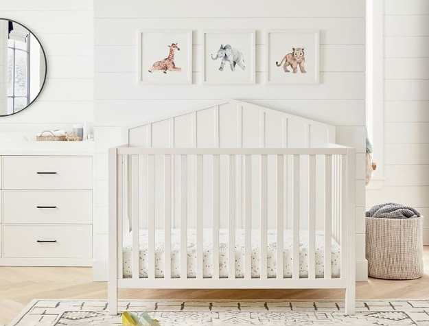 Baby Lion Framed Art alongside an elephant and giraffe print hanging over a white crib.