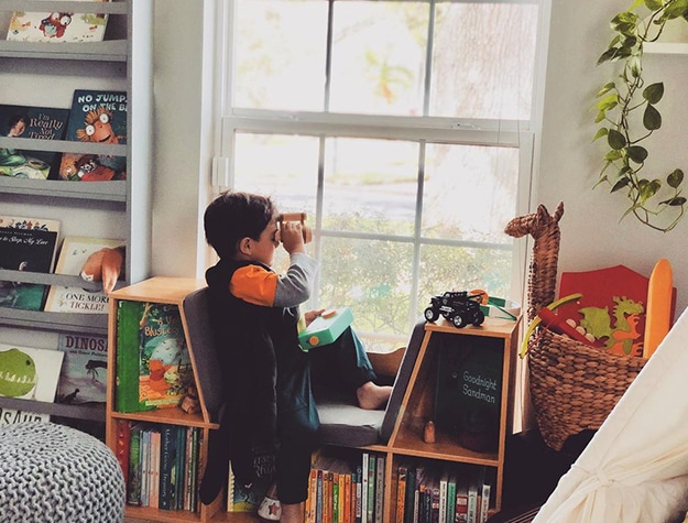 Child looking out large window bookshelf