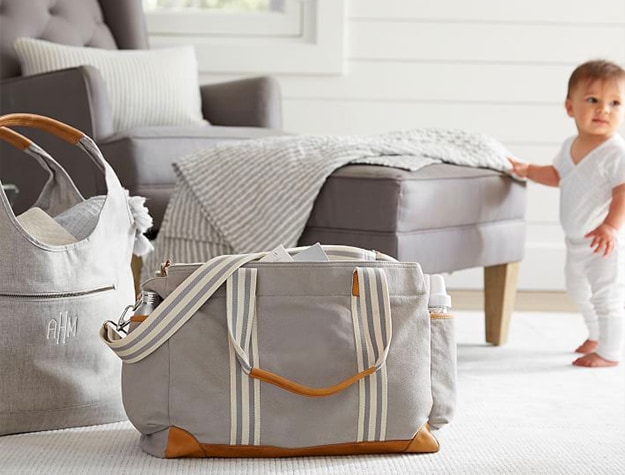 gray diaper bag with white and gray striped straps and leather details