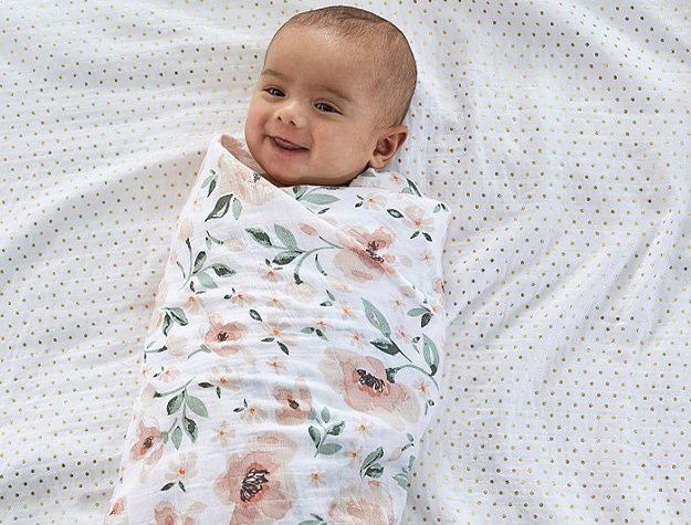 Baby wrapped in Meredith floral print muslin baby swaddle.